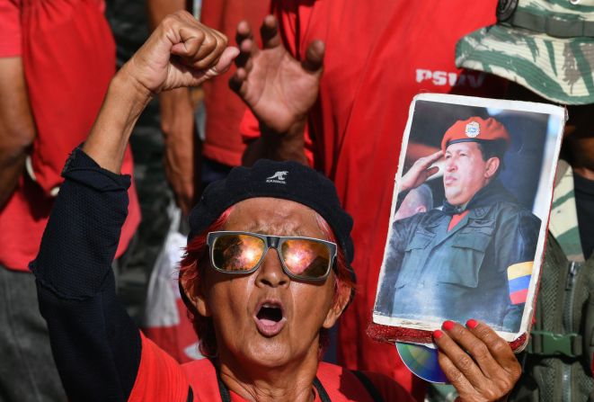 Un partidario del presidente de Venezuela, Nicolás Maduro, sostiene una foto del fallecido presidente venezolano Hugo Chávez, mientras grita arengas en favor del régimen.