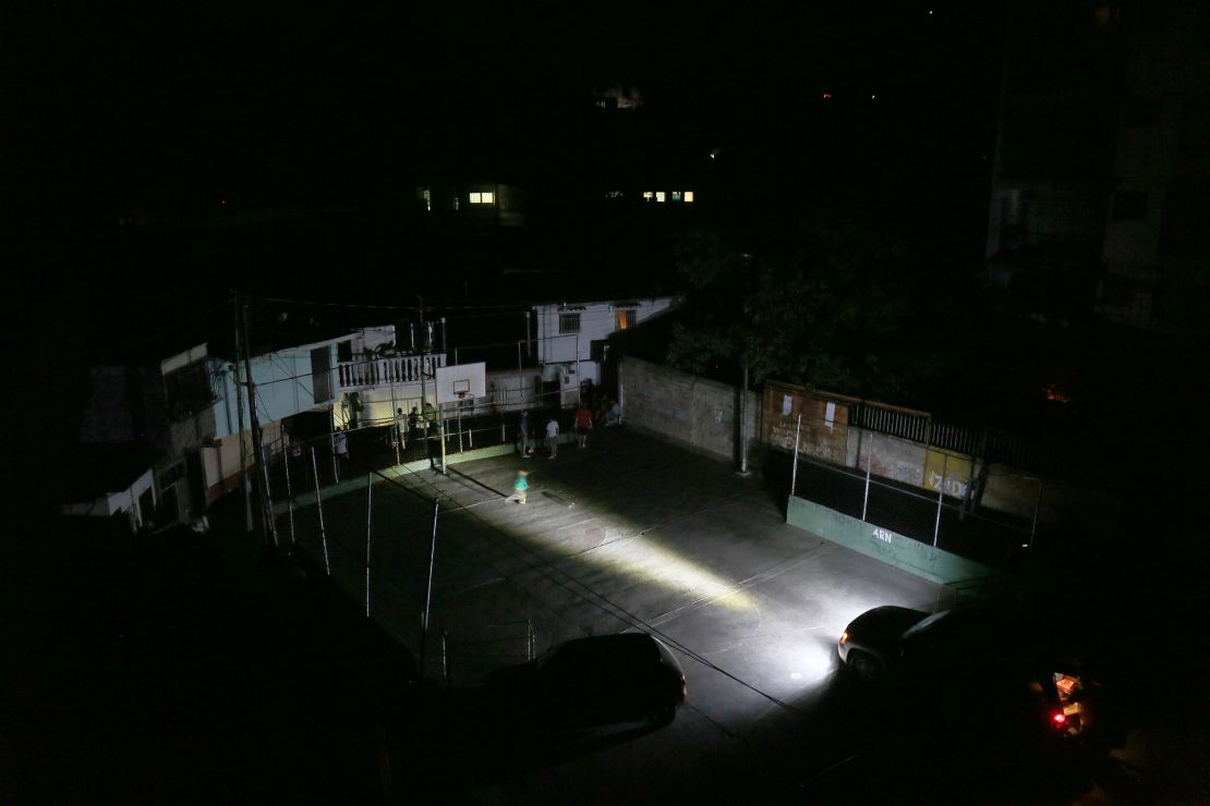 Vecinos usan las luces de un auto para alumbrar las calles de su barrio en Caracas.