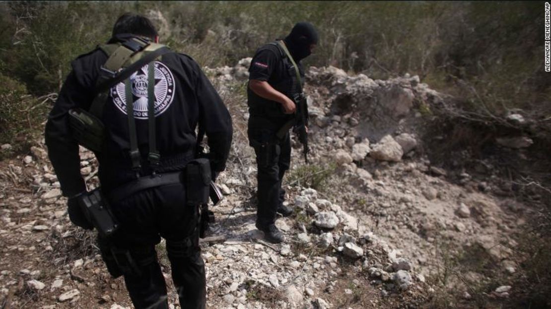 Los agentes de policía están parados junto a una fosa común cerca de San Fernando, México, en 2011. En ese momento, las autoridades dijeron que una banda de narcotraficantes estaba secuestrando a pasajeros de los autobuses y escondiendo a sus víctimas en tumbas ocultas.