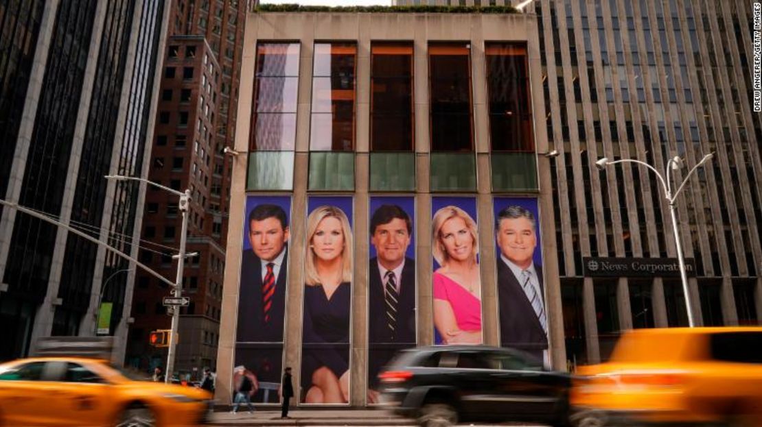 Los autos pasan en la Sexta Avenida de Nueva York por anuncios de personalidades de Fox News, como Bret Baier, Martha MacCallum, Tucker Carlson, Laura Ingraham y Sean Hannity, que adornan el frente del edificio de News Corporation.