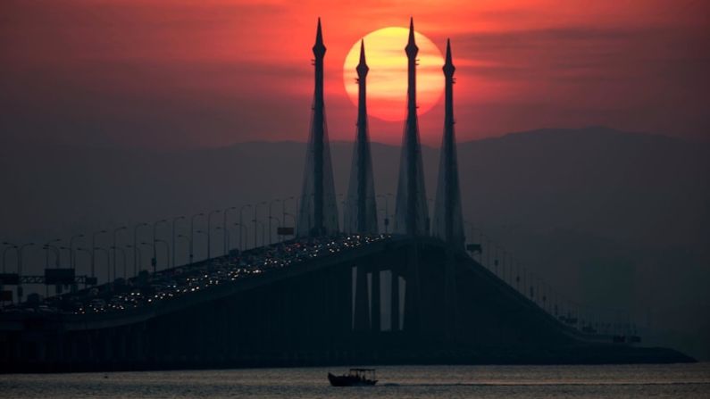 Penang, Malasia. El sol sale sobre el puente de Penang en la isla de Penang, donde los visitantes pueden explorar la selva tropical de Malasia, que alberga el 20% de las especies animales del mundo y las innumerables especies de plantas (Vincent Thian / AP).