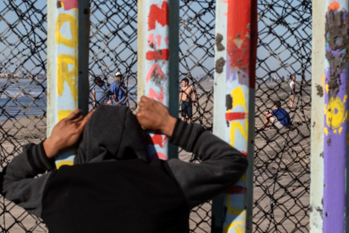 Un migrante centroamericano que espera llegar a los Estados Unidos mira a través de la valla fronteriza entre México y Estados Unidos en Playas de Tijuana, estado de Baja California, México.