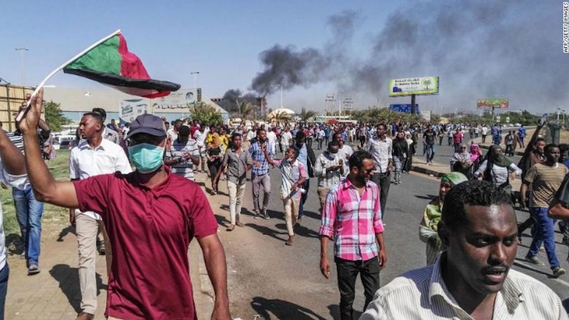 Manifestantes sudaneses ondean banderas nacionales al marchar hacia la sede del ejército.