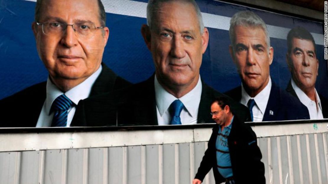 Un hombre árabe israelí camina frente a un anuncio electoral con las fotografías de los líderes del partido Azul y Blanco.