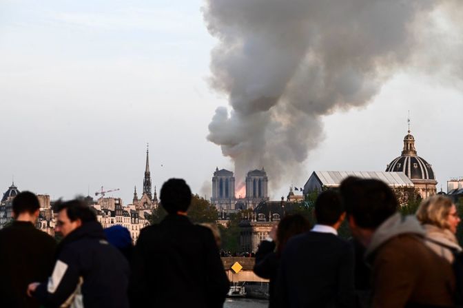 Personas ven desde lejos como las llamas consumen la icónica catedral de Notre Dame.