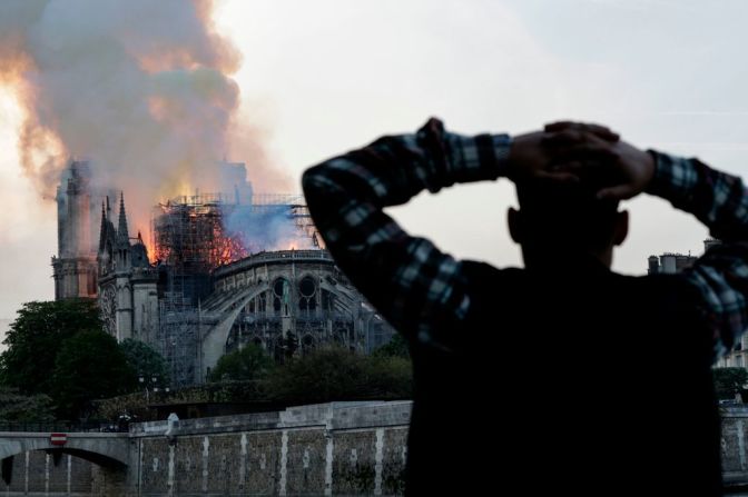 Un hombre mira mientras las llamas consumen la catedral.