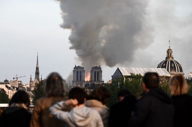 Los transeúntes observan las llamas y el humo que emanan de la catedral de Notre-Dame en París el 15 de abril de 2019. Crédito: PATRICK ANIDJAR / AFP / Getty Images