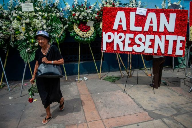 Una mujer llega a rendir homenaje al fallecido expresidente Alan García. Al fondo, un letrero con la inscripción "Alan presidente" a las afueras de la sede del APRA.