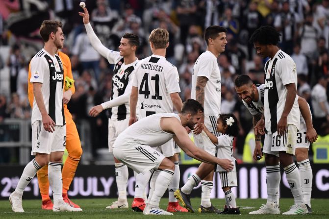 El mediocampista bosnio Miralem Pjanic toma a su hija en sus brazos mientras los jugadores, el colombiano Cuadrado entre ellos, celebran.