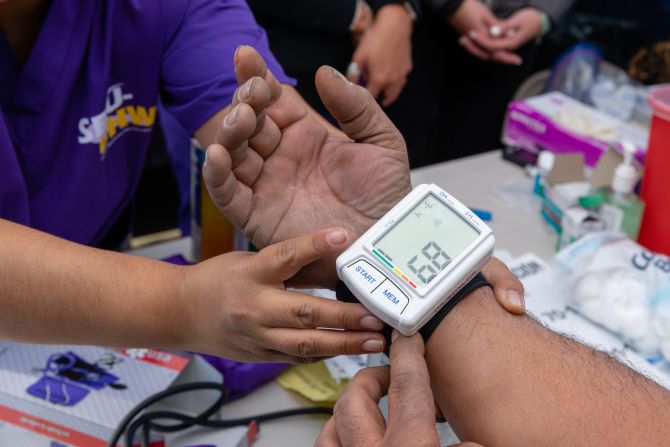 Las enfermeras voluntarias verifican los niveles de glucosa y presión arterial de los pacientes.