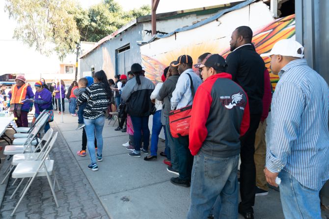 Hombres, mujeres y niños hacen fila para recibir tratamiento en la clínica móvil de voluntarios.