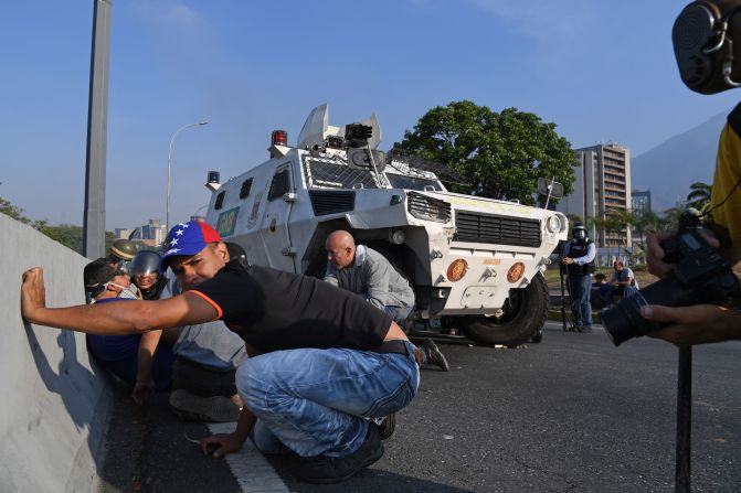 Venezolanos se protegen durante los enfrentamientos con las fuerzas de seguridad en Caracas el 30 de abril de 2019. Crédito: YURI CORTEZ / AFP / Getty Images