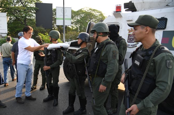 Un venezolano entrega comida a miembros de las fuerzas de seguridad en Caracas el 30 de abril de 2019. Crédito: YURI CORTEZ / AFP / Getty Images.