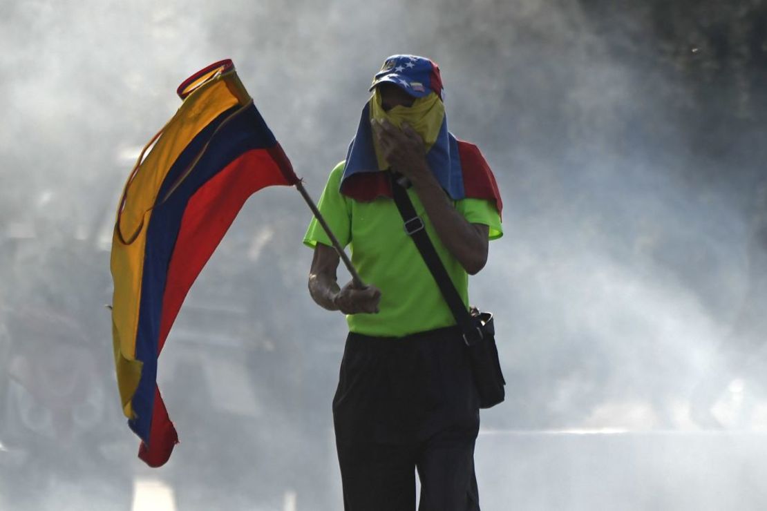 Un manifestante de la oposición sostiene una bandera de Venezuela en medio de disturbios con la miembros leales a Maduro de la Guardia Nacional Bolivariana. Crédito: FEDERICO PARRA/AFP/Getty Images.