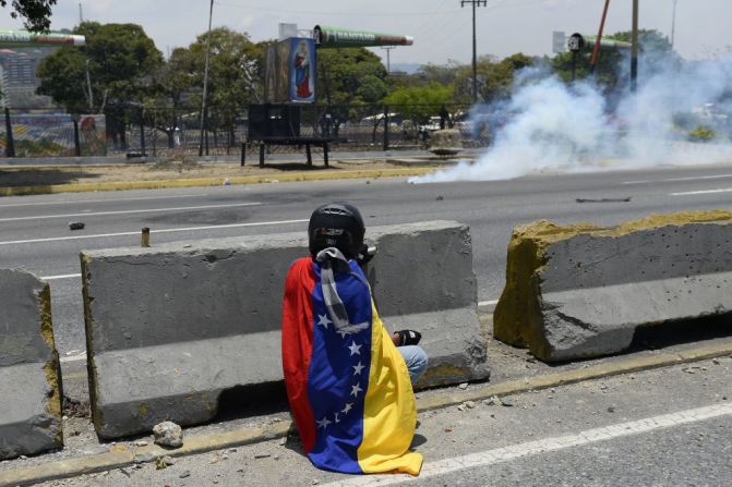 Un manifestante anti Gobierno se cubre tras lanzar una roca durante las protestas de este 1 de mayo en Venezuela, que llegan después de una jornada violenta de levantamiento cívico-militar.