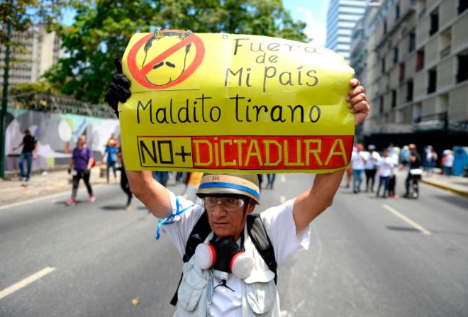 Un manifestante lleva un cartel con mensajes contra Maduro en una marcha de la oposición.