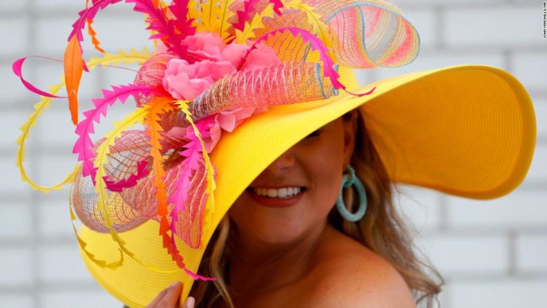 Una mujer luce su sombrero rosa y amarillo.