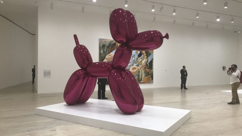 "Balloon Dog" o "Perro Globo" en color magenta es la pieza más icónica del Koons. En las esculutras pseudiinflables de Koons, crecend e manera similar una tensión y una circulación neumática debajo del reluciente acabado de esperjo, pero las formas infladas quizás no son tanto metáforas del deseo, sino una sublimación visualizada de este".