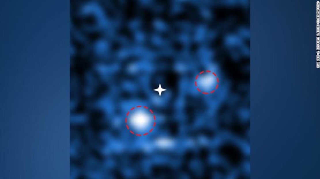 Dos planetas representados con los círculos blancos de luz, orbital la estrella en el centro de la imagen.