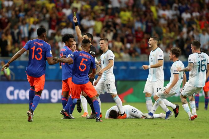 El árbitro Roberto Tobar muestra una tarjeta amarilla a Juan Cuadrado de Colombia después de una falta a Lionel Messi.