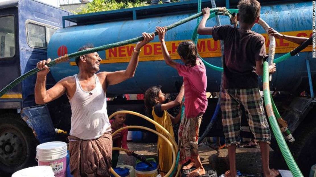 Residentes usan mangueras para sacar agua de un camión cisterna en Sanjay, Nueva Delhi.