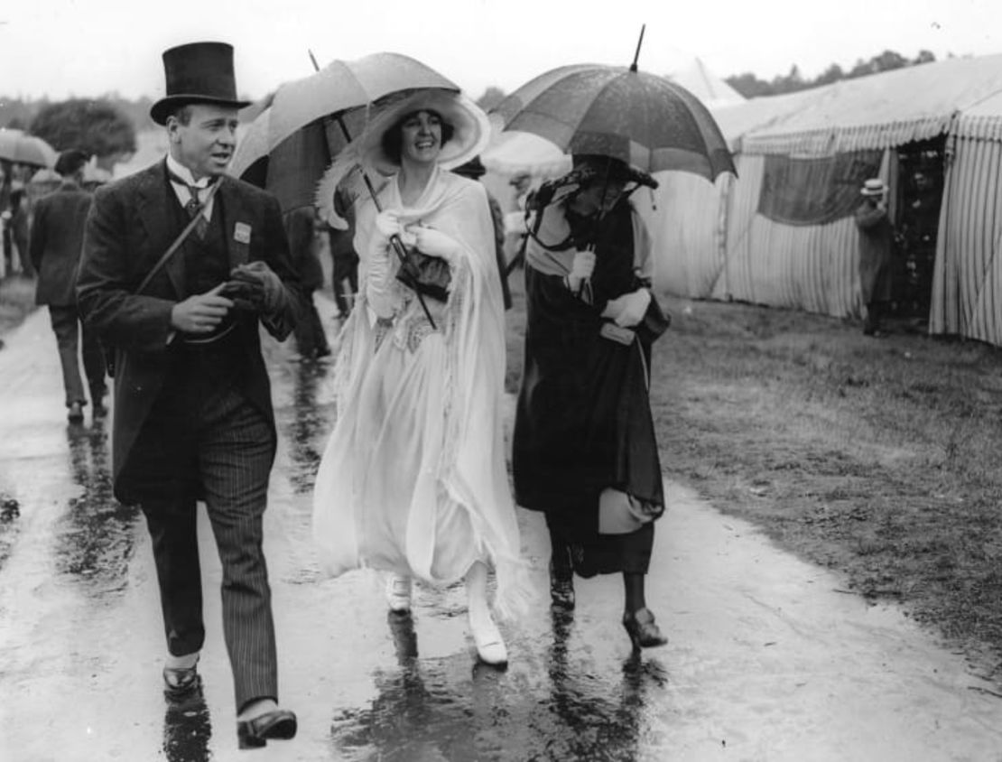 Mientras sus compañeros varones tradicionalmente vestían formales, las mujeres adoptaron siluetas más libres en Royal Ascot 1922, a pesar de la lluvia. Créditos: Agencia Topical Press /Archivo Hulton /Getty Images