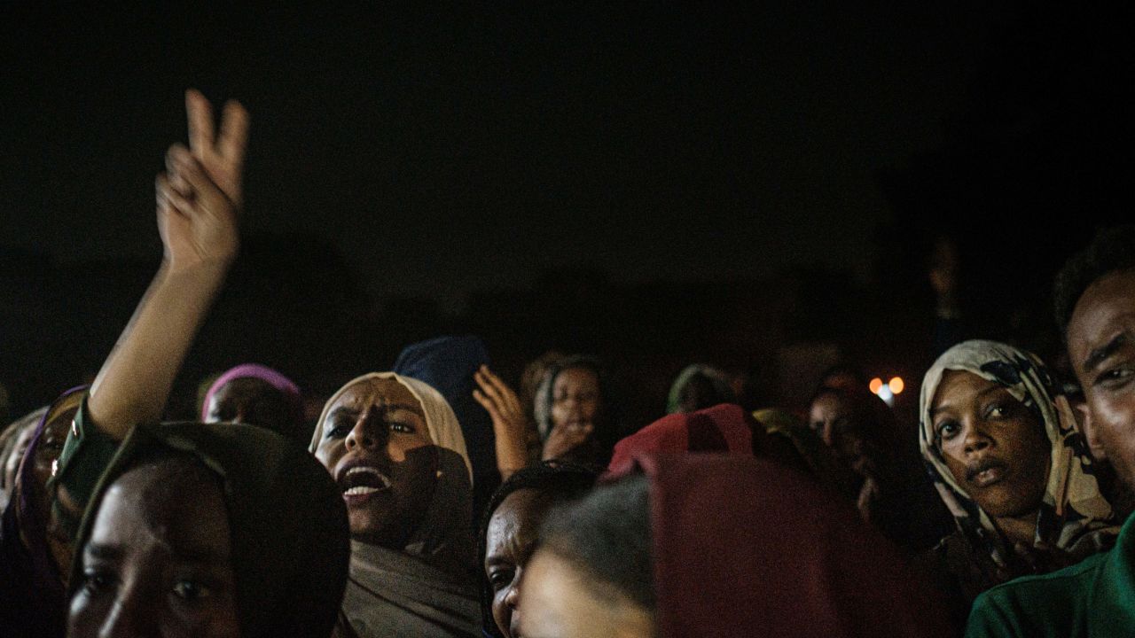 People chant slogans as a young man (not in picture) recites a poem, illuminated by mobile phones, before the opposition's direct dialog with people in Khartoum on June 19, 2019. - People chanted slogans including "revolution" and "civil" as the young man recited a poem about revolution. (Photo by Yasuyoshi CHIBA / AFP)