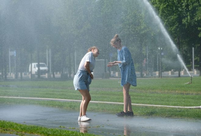 Dos jóvenes se refrescan con los aspersores frente a la cancillería en Berlín.