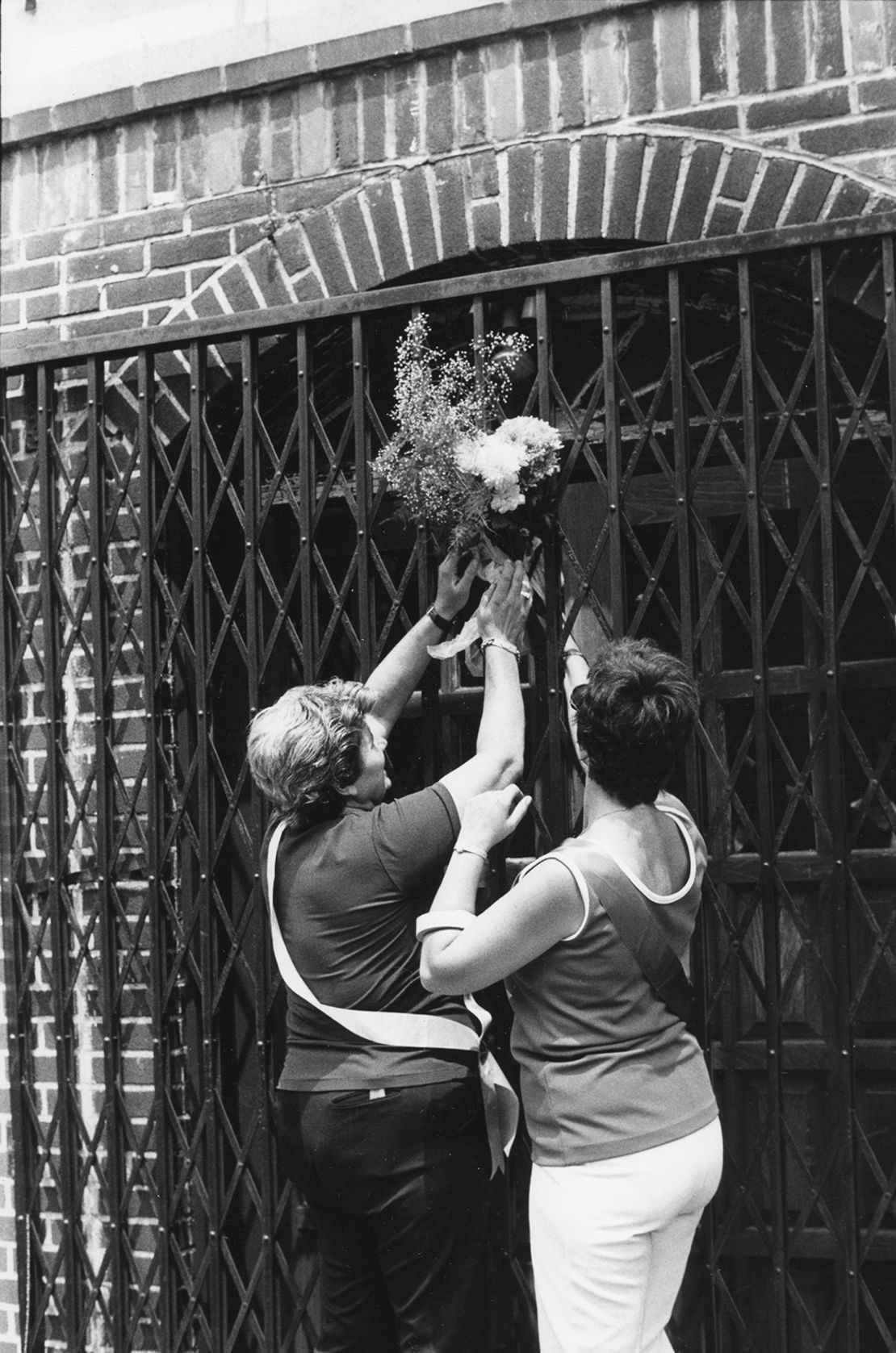 Jean DeVente, a la izquierda, y una amiga, colocan un ramo en la entrada de Stonewall para conmemorar el quinto aniversario de los disturbios.