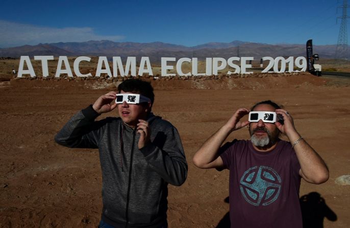 Turistas prueban las gafas especiales para ver el eclipse a la entrada de un campo astronómico en el que los expertos recibirán a miles de turistas para observar el eclipse solar total de este 2 de julio en Vallenar, en el desierto de Atacama, a unos 600 kilómetros al norte de Santiago de Chile, Chile.