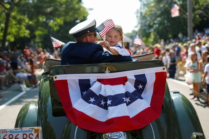 Una niña levanta una bandera estadounidense durante el desfile en Barnstable Village en Cape Cod, Massachusetts.