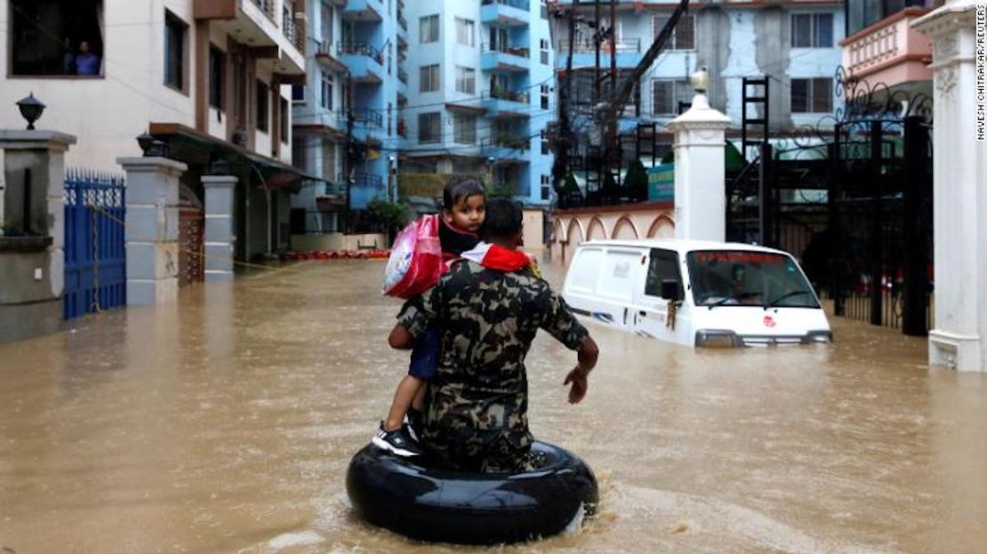 Un miembro del Ejército nepalí que lleva a un niño camina a lo largo de un barrio inundado en Katmandú, Nepal, el 12 de julio de 2019.