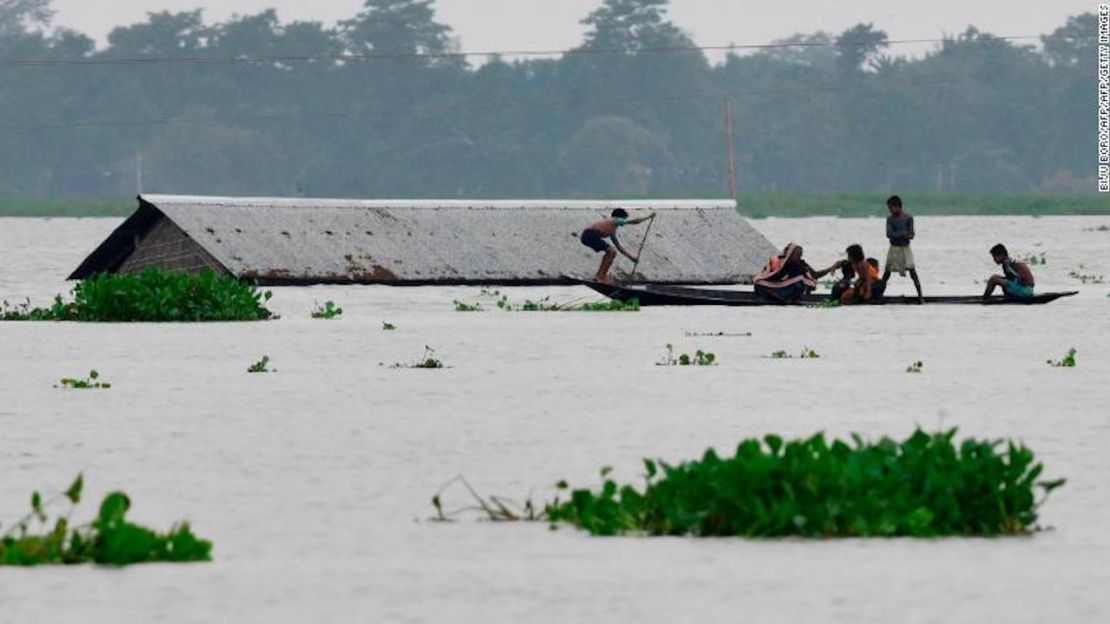 Aldeanos viajan a bordo de un bote cerca de una casa en el distrito Morigaon del estado Assam de la India el 15 de julio de 2019.