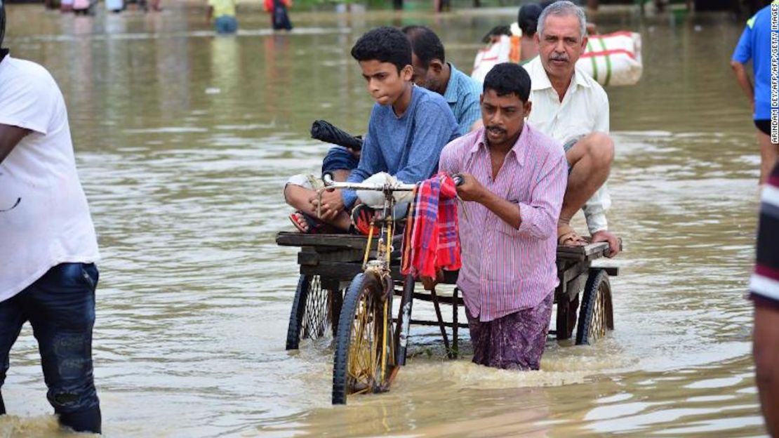 Un transportador de rickshaw indio transporta pasajeros a una calle inundada en el estado indio de Tripura, el 14 de julio de 2019.