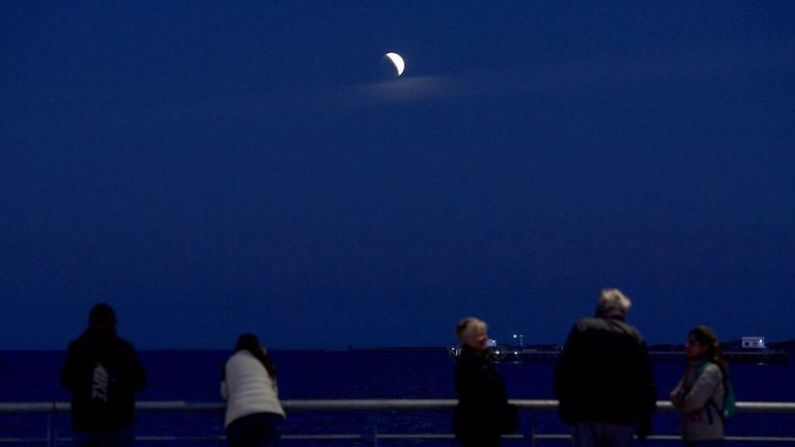 Personas observan el eclipse parcial lunar en el Río de la Plata en Buenos Aires.