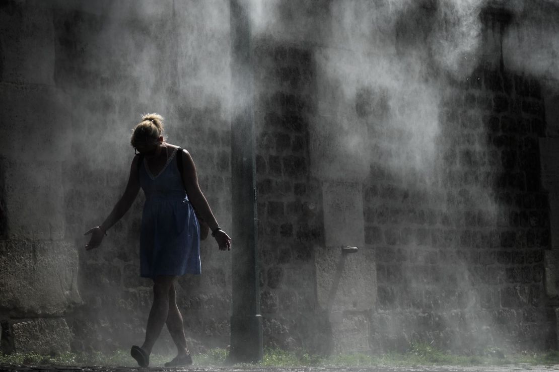 Una mujer se refresca bajo las duchas de spray públicas en un banco del río Sena en París el 25 de julio de 2019, durante la segunda ola de calor del año.