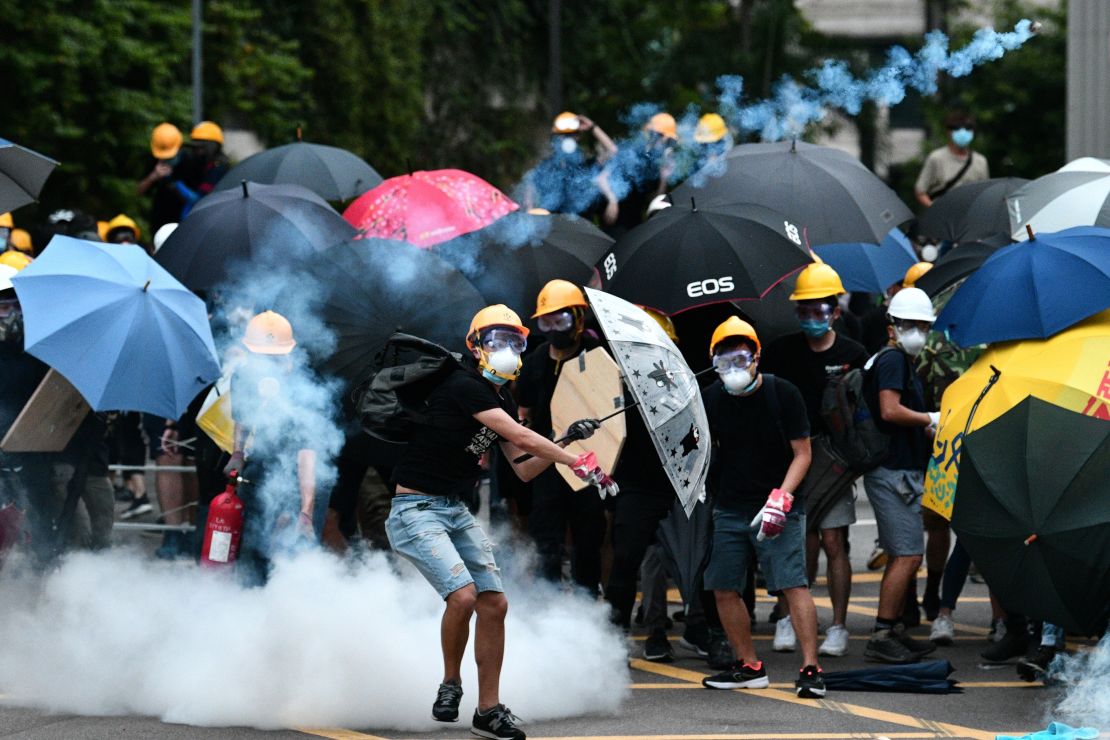 Un manifestante devuelve una bomba de gas lacrimógeno disparada por la policía durante una manifestación en el distrito de Yuen Long, en Hong Kong.