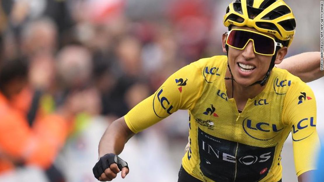 Egan Bernal, vistiendo la camiseta amarilla del líder, celebra cuando cruza la línea de meta.