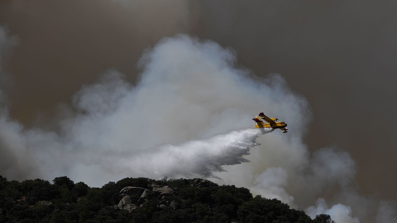 A Canadair drops water over a wildfire in the outskirts of Cenicientos in central Spain on June 29, 2019. - Spain was hit by more wildfires as temperatures remained sky-high in the Europe-wide heatwave, authorities said, just as firefighters finally managed to contain another blaze they had been tackling for nearly 72 hours. (Photo by PIERRE-PHILIPPE MARCOU / AFP)