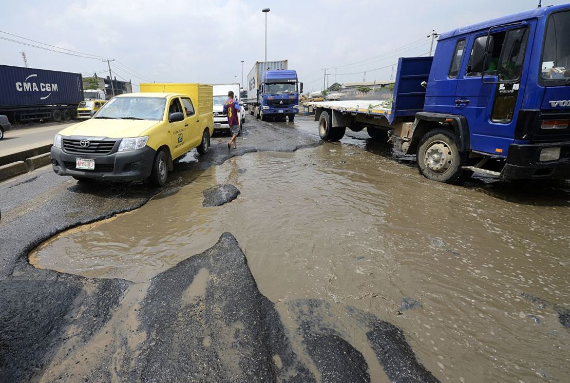 Morotists stuck in jams on waterlogged potholes on Apapa Oshodi expressway that leads to Apapa ports,  West Africa's busiest and largest container terminal on October 20, 2014 in Lagos.  Many roads lack proper drainage, turning them into swimming pools within minutes of a downpour; roadside culverts overflow; tarmac disintegrates; traffic lights and road signs are often absent. The poor state of Nigeria's roads is an exasperating joke for the country's long-suffering population but there are still hopes that improvements can be made. AFP PHOTO/PIUS UTOMI EKPEI