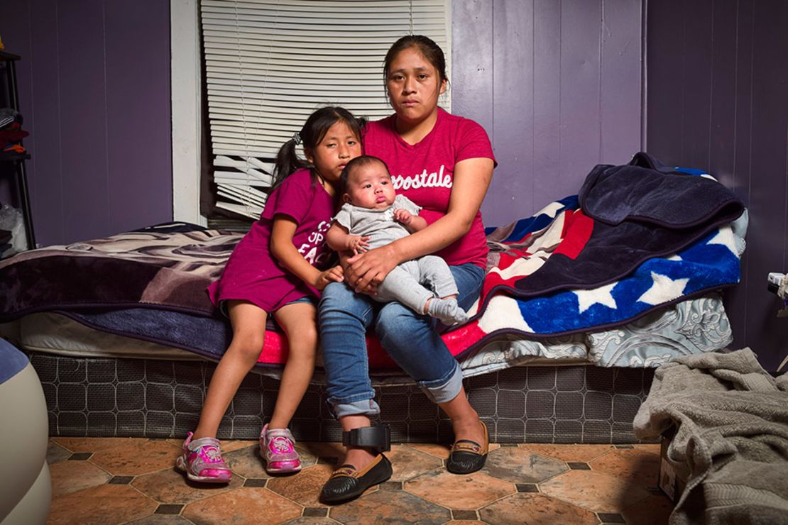 Isabella Gregorio Alonzo, de 27 años, posa para un retrato con sus hijas Juana, de 7 años, y Angelina, de 3 meses, en la casa que comparte con otros inmigrantes en Forest, Mississippi. Tanto Gregorio como su esposo fueron detenidos. Fue liberada con un monitor de tobillo, que se puede ver en su pierna derecha.