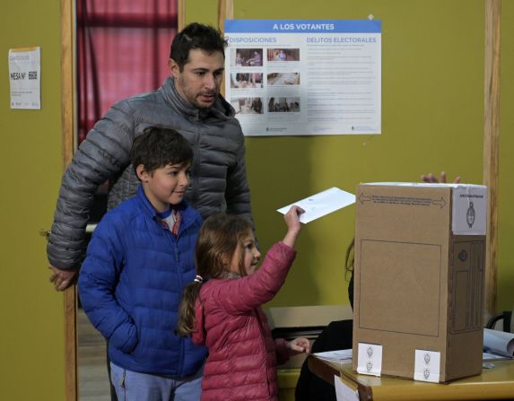 Una niña emite el voto de su padre durante las elecciones primarias en Buenos Aires, Argentina.