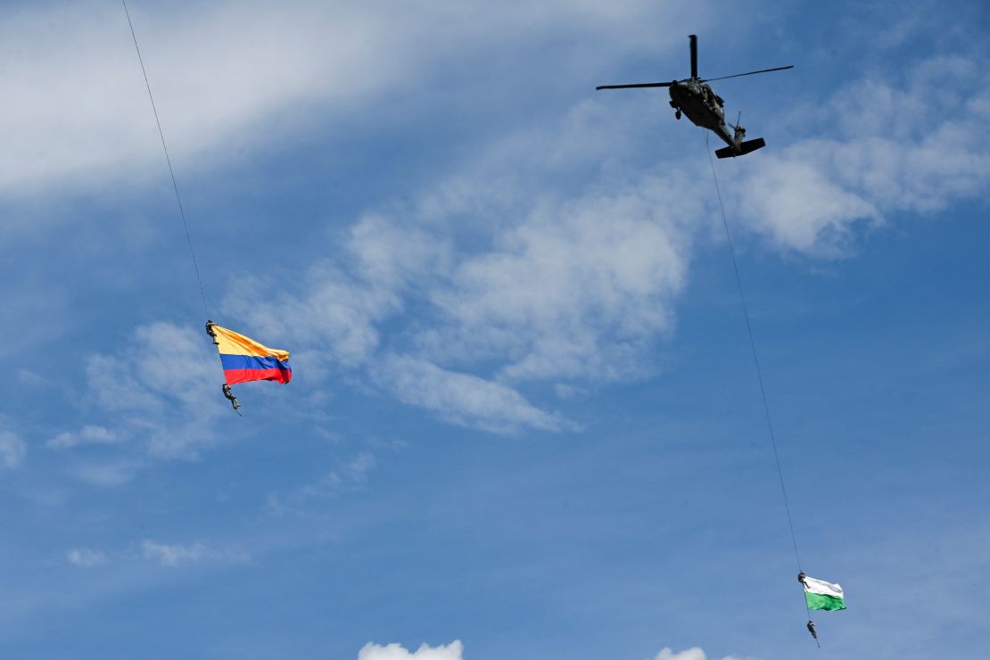 Los miembros de la Fuerza Aérea Jesús Mosquera y Sebastián Gamboa cuelgan de un helicóptero mientras ondean una bandera colombiana, como parte de una actuación durante el Festival de las Flores en Medellín, Colombia. Mosquera y Gamboa murieron accidentalmente después de caerse cuando aún colgaban del avión antes de aterrizar en un aeropuerto local.