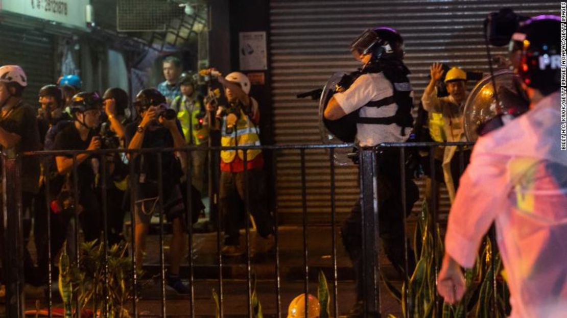 Los oficiales de policía de una ciudad de Hong Kong apuntan con un arma cuando los enfrentamientos entre manifestantes prodemocráticos y la policía aumentaron el domingo por la noche.