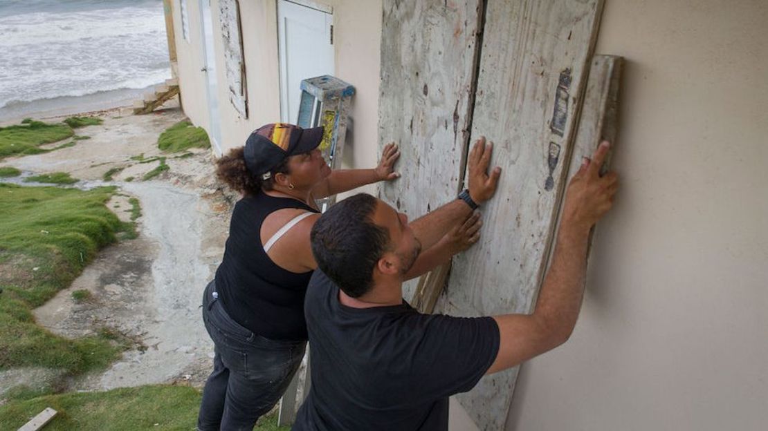 Una pareja instala protecciones de madera en su casa en Yabucoa, Puerto Rico, ante la inminente llegada de la tormenta Dorian.