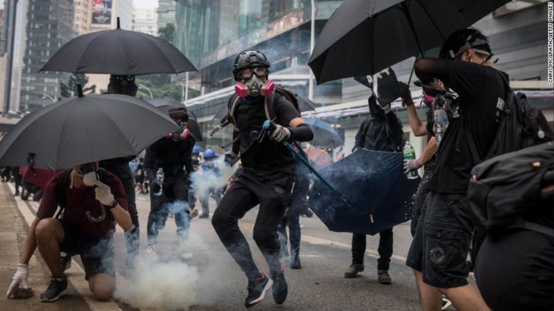 Un manifestante en favor de la democracia arroja una bomba de gas lacrimógeno a la policía en medio de enfrentamientos el domingo.