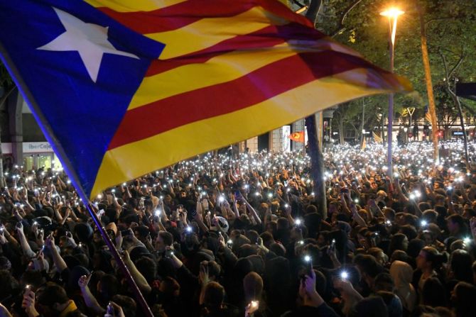 Manifestantes enarbolan la bandera "Estelada" proindependentista catalana. (Photo by LLUIS GENE / AFP).