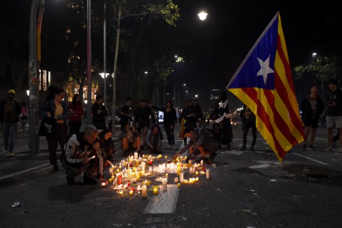 Manifestantes encienden velas junto a una bandera independentista catalana en protesta por las sentencias contra los líderes separatistas.