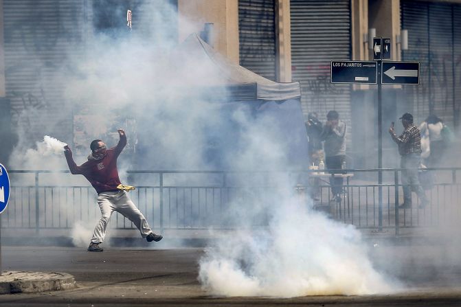 Un manifestante arroja una lata de gas lacrimógeno durante los disturbios en las protestas.