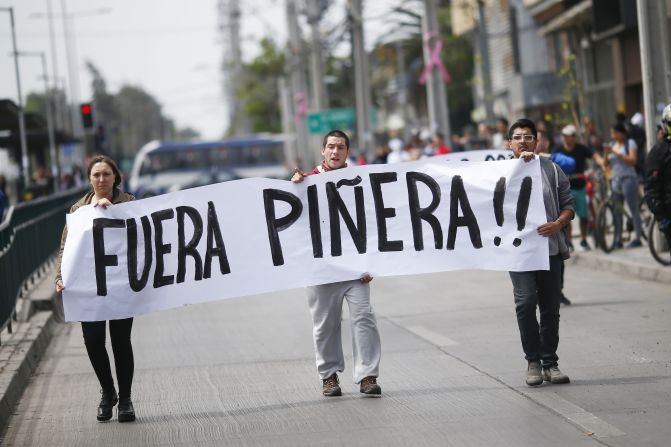 "Fuera Piñera", dice el letrero que llevan dos manifestantes en Santiago de Chile este sábado 19 de octubre.